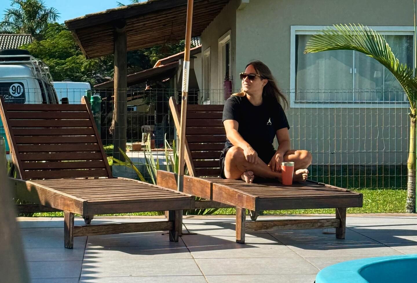Espreguiçadeiras de madeira à beira da piscina em dia de sol